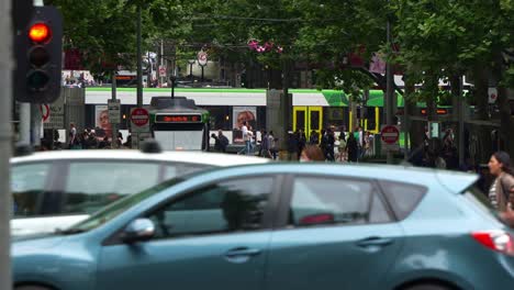 Busy-traffic-on-the-Swanston-street-in-downtown-Melbourne-bustling's-central-business-district-with-pedestrians-crossing,-cars-and-buses-driving-along-the-street,-hustle-and-bustle-of-urban-life