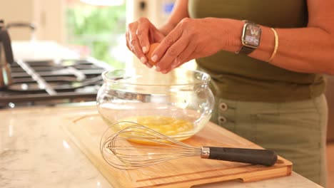 Side-angel-close-up-of-a-woman-cracking-eggs-into-a-bowl-in-a-modern-kitchen