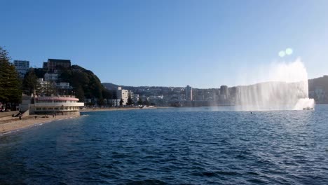 Popular-Bahía-Oriental-Con-Playas-De-Arena-Y-Fuente-De-Agua-En-El-Puerto-Con-Un-Vistazo-Del-Paisaje-Urbano-A-Lo-Lejos-En-Wellington,-Nueva-Zelanda-Aotearoa