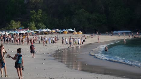 Tourists,-Visitors-walk-coastline-Crystal-Bay-Beach,-Nusa-Penida,-Indonesia