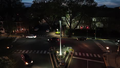 Aerial-approaching-shot-of-traffic-on-junction-at-night-with-american-flag