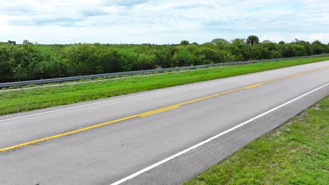 Everglades-road-sign-and-aerial-rising-shot-over-road-towards-sprawling-green-nature