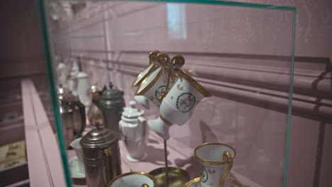 Glass-display-case-showcasing-antique-porcelain-cups-and-other-vintage-items-in-the-Chocolate-Museum-in-Zagreb,-Croatia