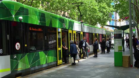 Tram-arrived-at-the-stop-with-commuters-disembarking-and-boarding-the-tram-on-Bourke-street-in-Melbourne-city's-bustling-Central-Business-District