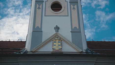 Close-up-of-a-church-facade-with-a-coat-of-arms-and-architectural-details-in-King-Tomislav-Square,-Varaždin,-Croatia