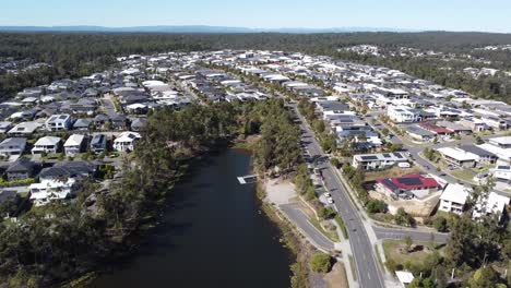 Drone-Volando-Sobre-Un-Lago-Artificial-Hacia-Un-Suburbio-Densamente-Poblado-En-Australia