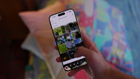 Eine-Person,-Die-Ein-Smartphone-Hält,-Betrachtet-Zu-Hause-Sitzend-Eine-Sammlung-Von-Bildern-In-Einer-Fotogalerie-App-Und-Konzentriert-Sich-Auf-Einen-Klaren-Und-Hellen-Bildschirm,-Auf-Dem-Verschiedene-Momente-Gezeigt-Werden