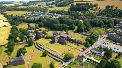 Exuberante-Campiña-Aérea-En-Las-Fronteras-Escocesas-Con-El-Hito-De-La-Abadía-De-Melrose-Debajo,-Melrose,-Escocia,-Reino-Unido