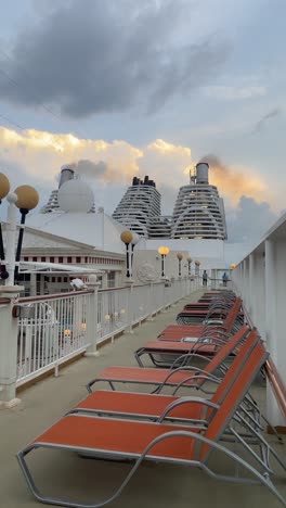 Row-Of-Chaise-On-Upper-Deck-Luxury-Cruise-Ship-With-Chimney-On-The-Background