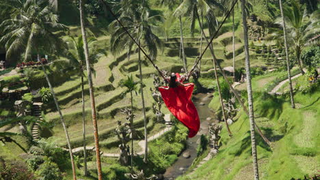 Touristin-Im-Langen-Roten-Kleid-Auf-Bali-Schaukel-Mit-Blick-Auf-Reisterrassen