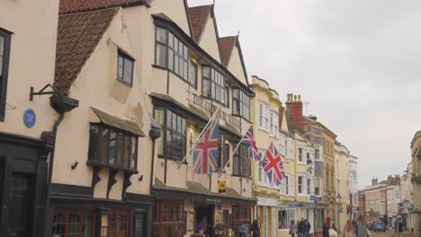 Charming-street-in-Wells,-England's-smallest-city,-showcasing-traditional-buildings-and-Union-Jack-flags