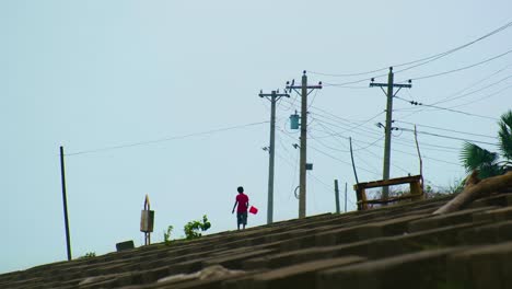 Niño-Pequeño-Con-Un-Cubo-De-Plástico-Caminando-Por-Un-Terraplén-De-Hormigón