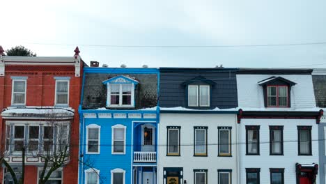 Rising-drone-shot-showing-colorful-townhouses-during-snowy-winter-day-in-American-Suburb