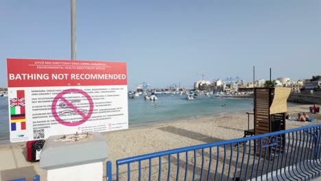 Swimming-people-behind-a-bathing-not-recommended-sign-due-to-temporary-contamination-at-St