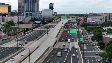 Drone-footage-of-a-busy-freeway-in-downtown-Orlando,-Florida-with-multiple-lanes-of-traffic,-surrounding-buildings,-and-signage