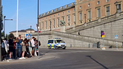 Police-van-drives-by-Stockholm-Palace-on-Sweden’s-National-Day,-wide-view-slomo