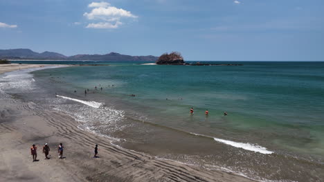 Aerial-view-rising-over-people-at-a-beach,-sunny-day-in-Guanacaste,-Costa-Rica