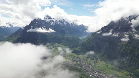 Fronalpstock-Glarus-Switzerland-aerial-through-the-clouds-to-reveal-the-village-below