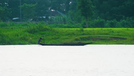 Hombre-Remando-Una-Gran-Canoa-De-Madera-A-Través-De-Un-Río-Inundado-En-Bangladesh