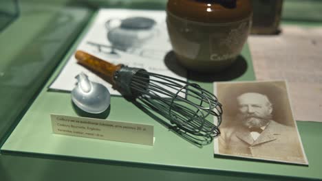 Display-case-in-the-Chocolate-Museum-in-Zagreb-featuring-antique-chocolate-making-tools,-an-old-photograph,-and-historical-documents