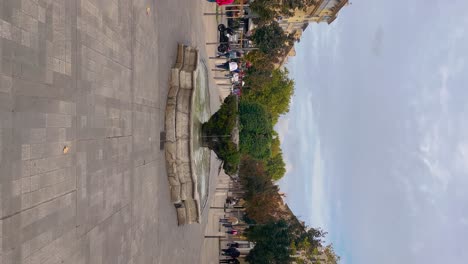 People-walk-by-fountain-on-Cours-Mirabeau-in-Aix-en-Provence,-vertical