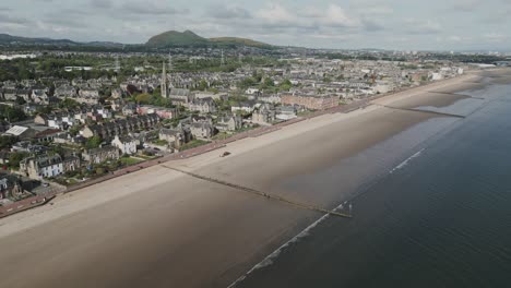 Seaside-town-in-Edinburgh,-Scotland,-with-promenade-and-beach-at-low-tide-with-groynes