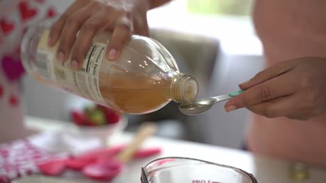 Pouring-a-teaspoon-of-apple-cider-vinegar-making-a-special-valentine's-day-cake-vegan-chocolate-cake-eggless-plant-based-dairy-free