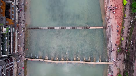 Toma-Aérea-De-Arriba-Hacia-Abajo-Descendiendo-Hasta-Un-Puente-De-Madera-Y-Piedras-Empinadas-En-Tuo-Jiang