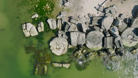 Beautiful-aerial-establishing-view-of-Karosta-concrete-coast-fortification-ruins,-calm-Baltic-sea,-sunny-summer-day,-birdseye-drone-dolly-shot-moving-right