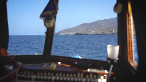 Blick-Aus-Der-Kabine-Eines-Bootes-Mit-Blick-Auf-Das-Meer-Und-Einen-Entfernten-Leuchtturm-Durch-Das-Fenster