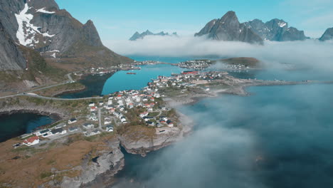 Lofoten-Islands,-Norway:-Aerial-Shot-over-Clouds-and-Mountains"-of-the-fishing-town-of-Reine