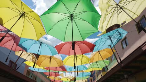 Walking-POV-along-Colorful-umbrellas-in-the-street-of-historic-town-of-Guatapé,-Colombia