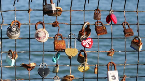 Love-Lockets-Padlocked-on-a-Fence-with-Ocean-Water-Blurred-in-Background,-San-Francisco,-California,-USA