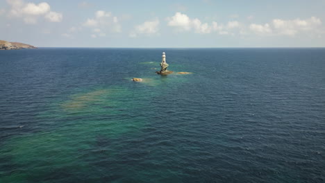 Coastal-Serene-scene-featuring-solitary-lighthouse-perched-on-a-rocky-outcrop,-surrounded-by-calm-blue-waters-and-rugged-hills-under-a-clear-sky