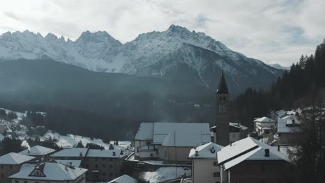 Pan-De-Ciudad-Del-Valle-De-Montaña-Cubierto-De-Nieve-Rodeada-De-Bosques-Alpinos