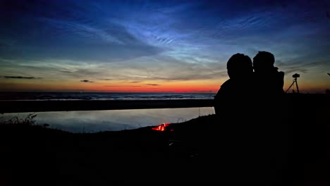 Couple-hugging,-romantic-showing-affection-near-campfire-at-the-sea-after-sunset