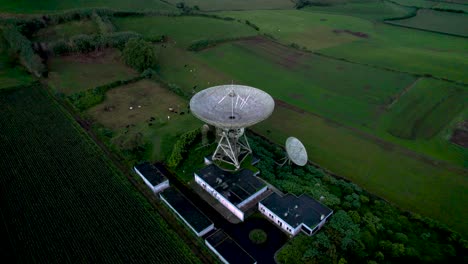 Aerial-shot-of-an-abandoned-communication-satellite-surrounded-by-beautiful-scenic-greenery-and-mountains-in-São-Miguel-Island,-Portugal