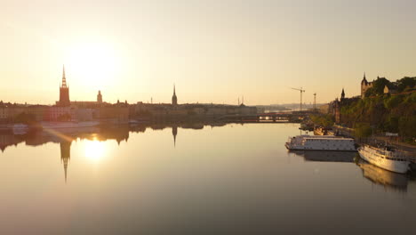 Gamla-Stan-skyline-reflection-in-glassy-calm-Riddarfjärden,-sunrise-aerial-view