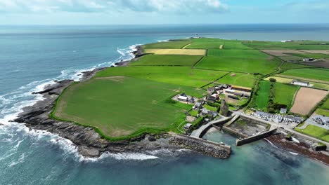 Irland-Epische-Orte-Drohnenlandschaft-Hook-Head-Wexford,-Slade-Village-Mit-Hook-Leuchtturm-Im-Hintergrund-An-Einem-Hellen-Sommertag