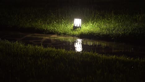 4K:-Rainy-night-scene-in-Georgia,-with-raindrops-falling-on-the-garden-ground-light