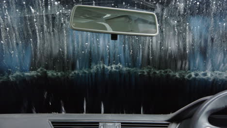 Rotating-brush-wash-car-windscreen-at-automatic-car-wash-service,-interior-view