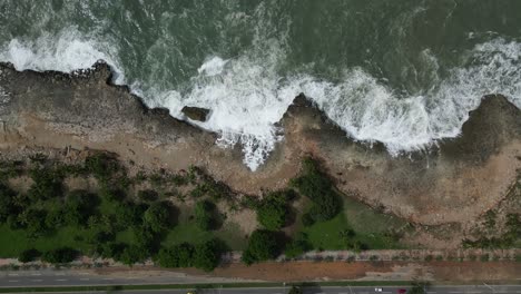 Aerial-top-down-view-of-ocean-waves-crash-against-rocky-coastline