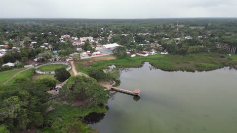 Aerial-descends-to-shoreline-dock-on-Laguna-Noh-Bec,-Mexico-pueblo