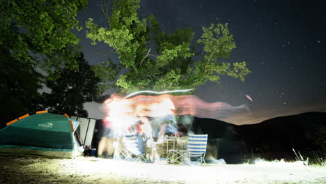 Eine-Gruppe-Von-Freunden,-Die-In-Der-Nähe-Eines-Bergsees-Unter-Dem-Sternenhimmel-Campen,-Mit-Lagerfeuer-Und-Aufgehender-Milchstraße-Im-Hintergrund