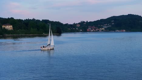 Sailboat-sailing-on-Maggiore-lake-surrounded-by-picturesque-hillside-town-in-Italy