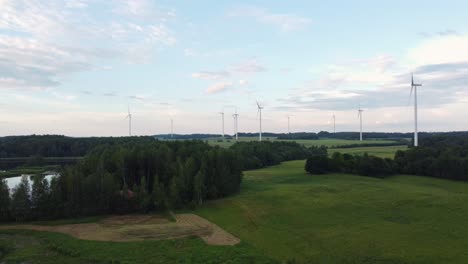 Many-wind-turbines-in-green-landscape,-aerial-descent-view