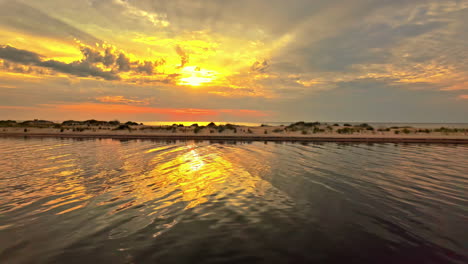 Beautiful-aerial-view-of-a-long-strip-or-sandy-peninsula-with-a-vibrant-sunset-in-the-background