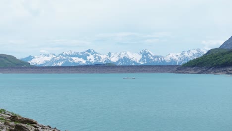 Aerial-view-of-Mount-Cenis-Lake-surrounded-by-snow-capped-mountains,-capturing-the-tranquility-of-nature-and-majestic-landscape-scenery