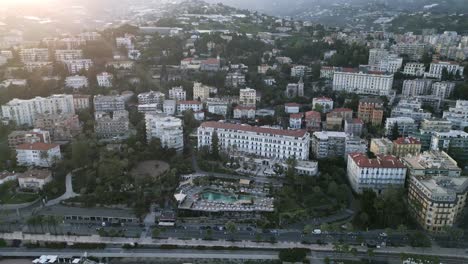 Drone-establishing-shot-of-apartment-and-hotel-buildings-along-hillside-of-Sanremo-Italy-as-sun-descends