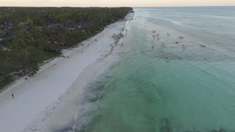 Walking-people-on-Pingwe-beach-with-boats-on-clear-ocean-shore-in-summer